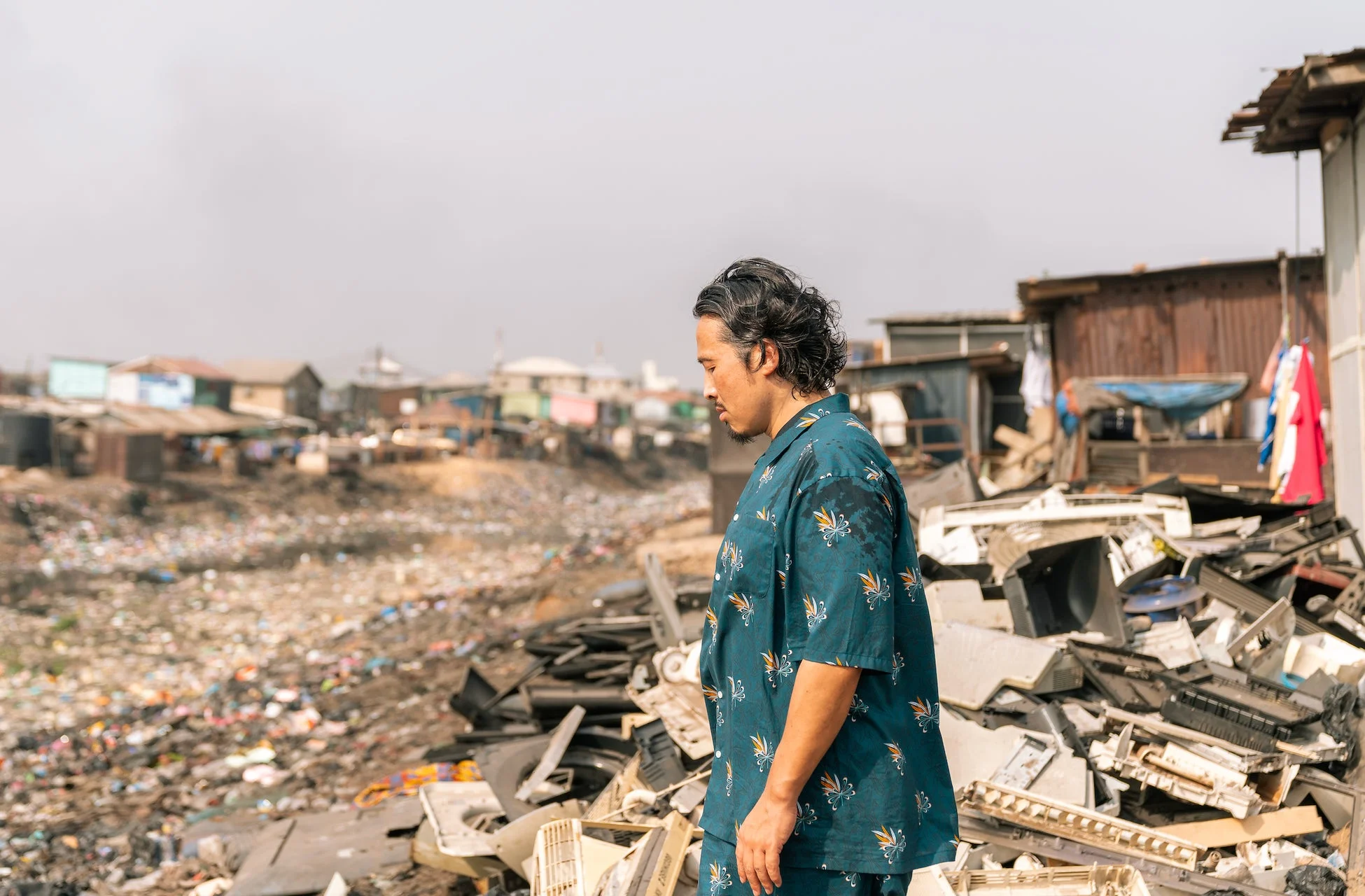 電子廃棄物集積地に立つ男性
