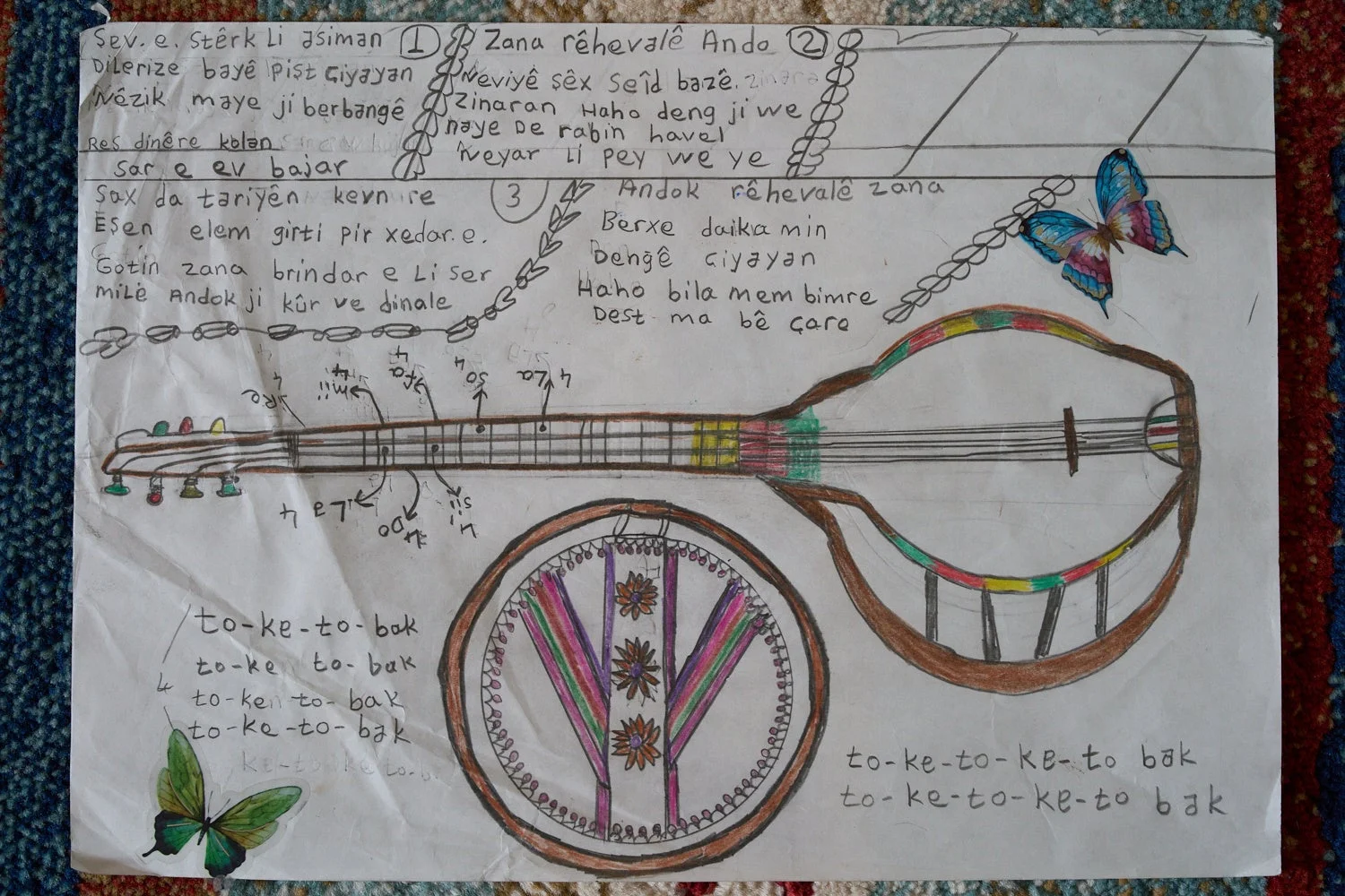 手書きの弦楽器のイラストと、クルド語のような言語で書かれた歌詞