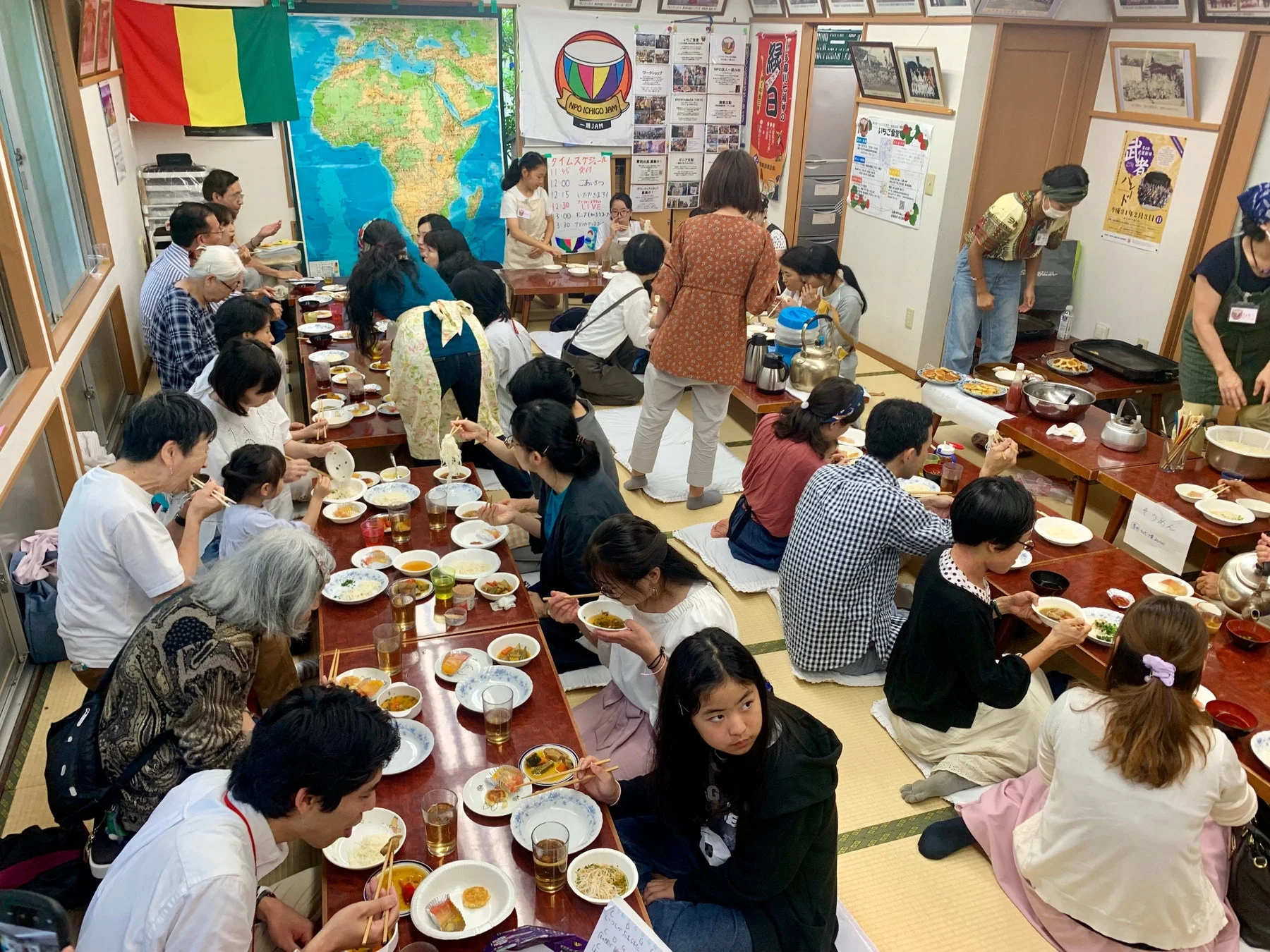 NPOいちごジャムが主催する多世代交流イベントの様子です。和室で多くの人々が低膳を囲み、そうめんなどを楽しんでいます。