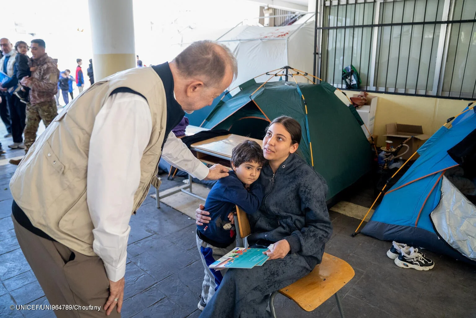 避難所で男性が母親と幼い子供に話しかけている