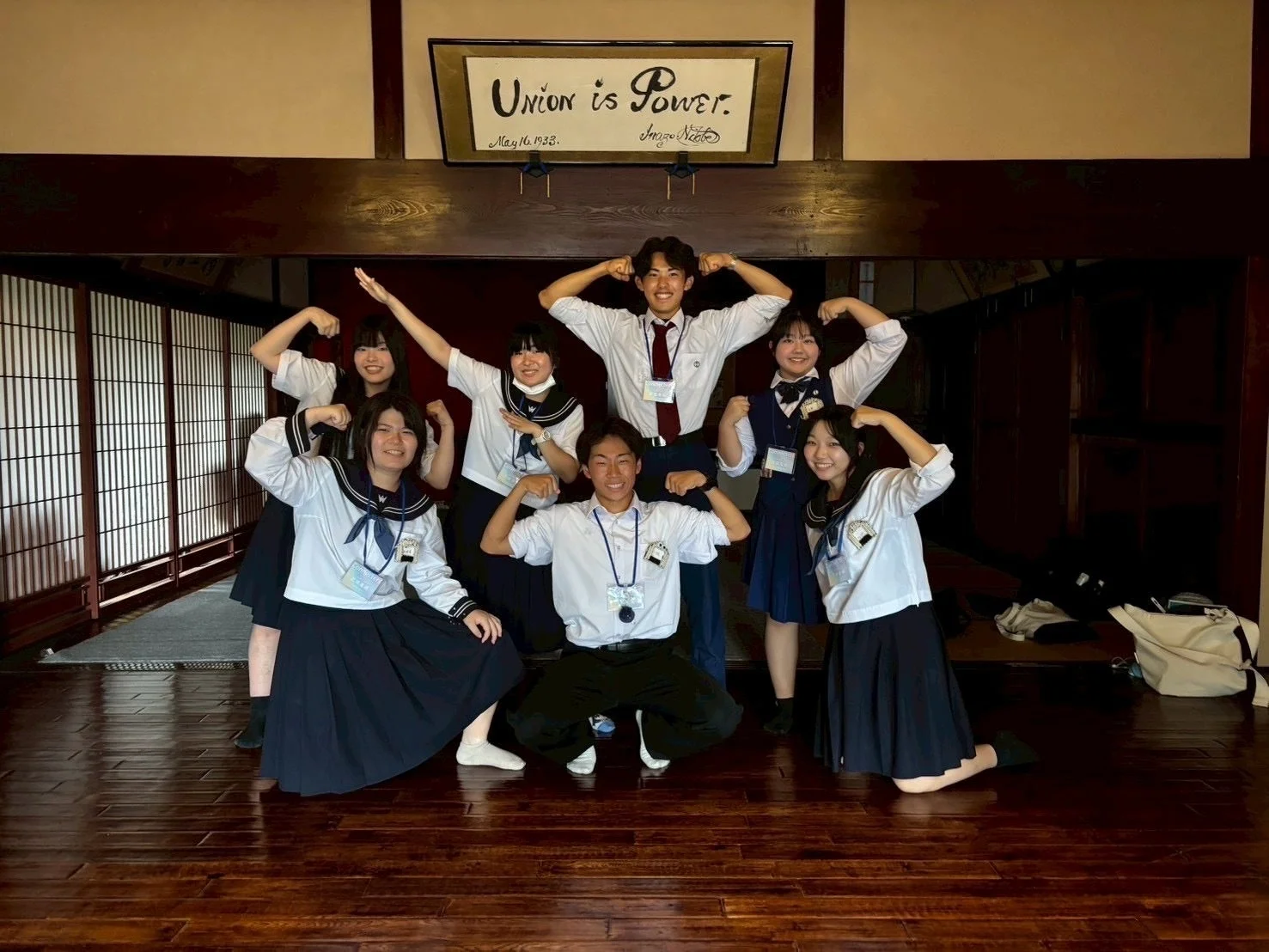 制服を着て力こぶを作る高校生たち