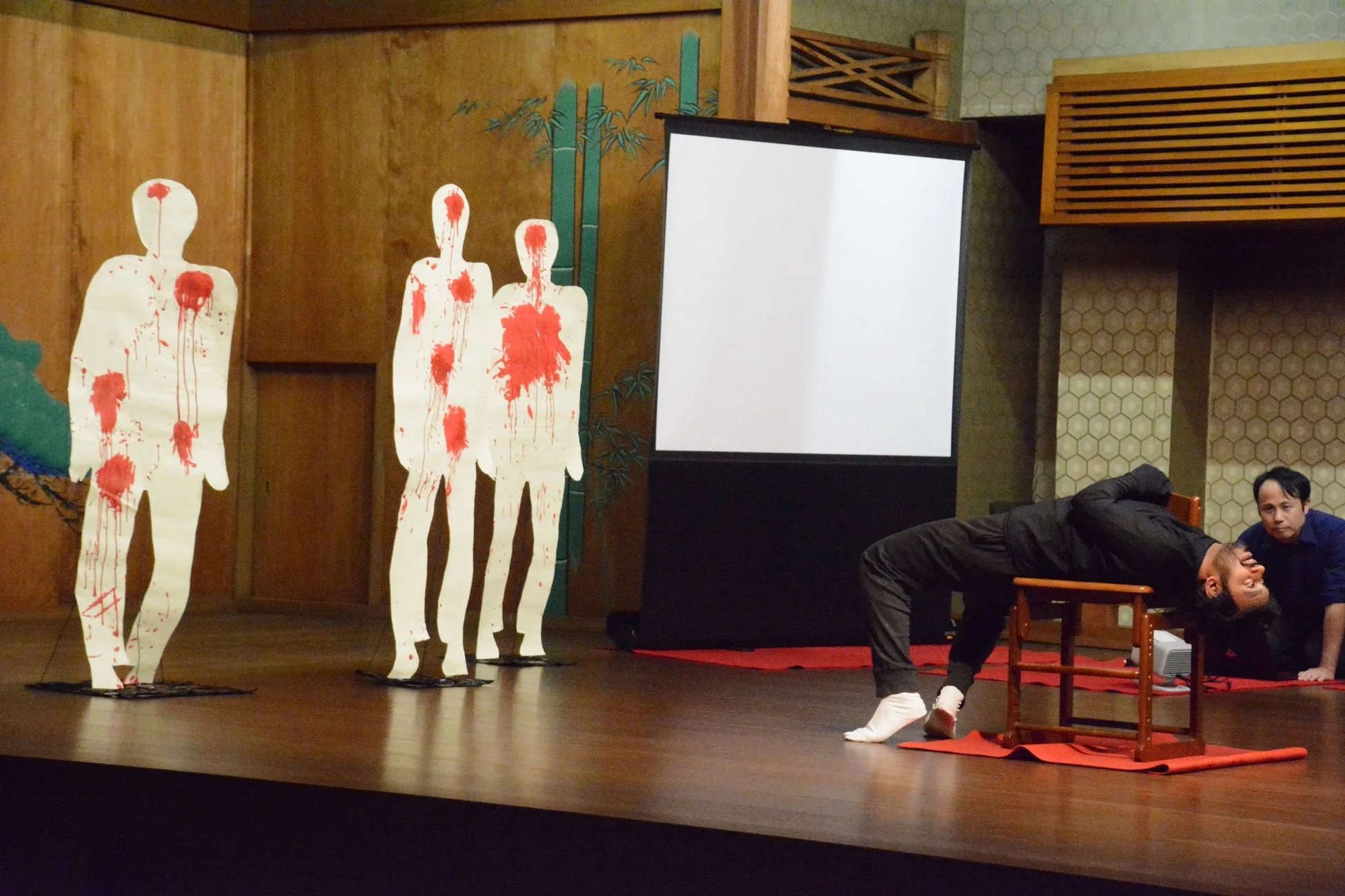 舞台上で、赤い塗料が飛び散った人型パネル