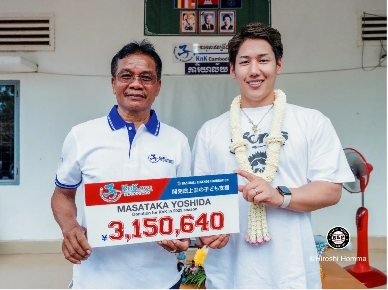 寄付額を示すボードを持つ男性2人