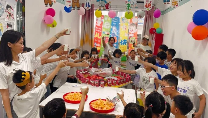 子供たちが大人と一緒に乾杯している様子