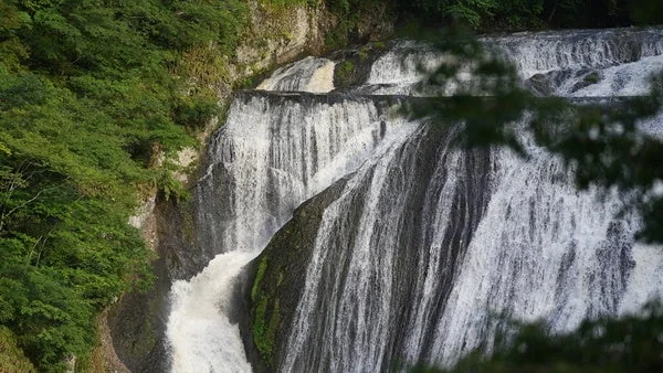 緑豊かな山肌を複数の段になって勢いよく流れ落ちる雄大な滝