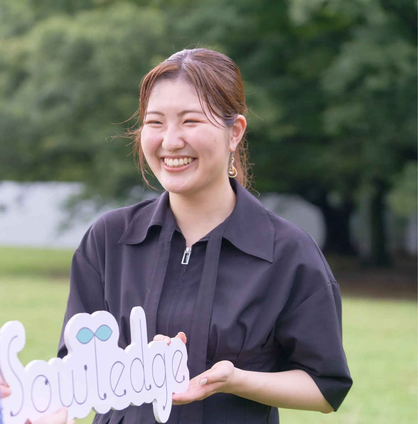 笑顔の女性がSowledgeのサインボードを持つ