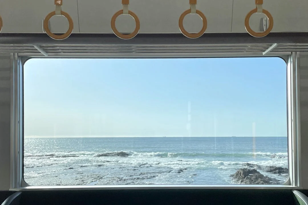 電車の窓から広がる青い海と青空の景色