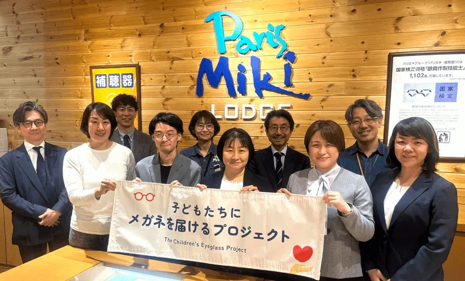 パリミキの従業員らしき人々が「子どもたちにメガネを届けるプロジェクト」のバナーを持ち、笑顔で写る集合写真です。
