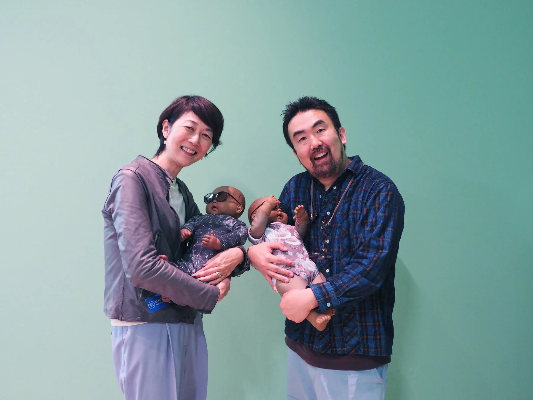 日本人,男女,カップル,笑顔,赤ちゃん人形,ロボットベビー,育児,子育て,サングラス,スタジオ撮影,緑色の背景,テクノロジー,教育,家族