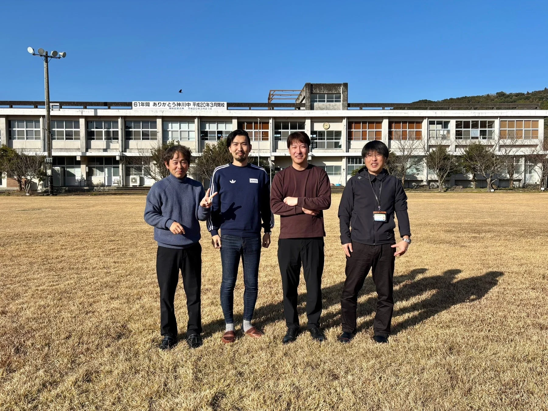 旧神川中学校を背景に立つ男性グループ